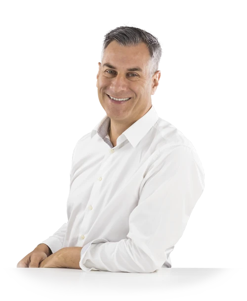 Jochen Muffler steht mit weißem Hemd an einen Tisch gelehnt und blickt lächelnd in die Kamera.